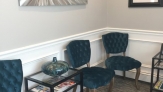 View of waiting room with new upholstered chairs, and side tables with decorative pieces underneath artwork on walls.