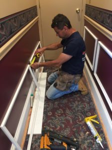 A contractor measures decorative fittings as he prepares to mount them on the walls.