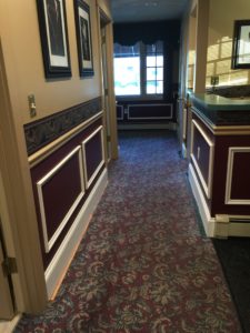 A newly renovated hallway with decorative wood framings, bump guard, and artwork on walls. 