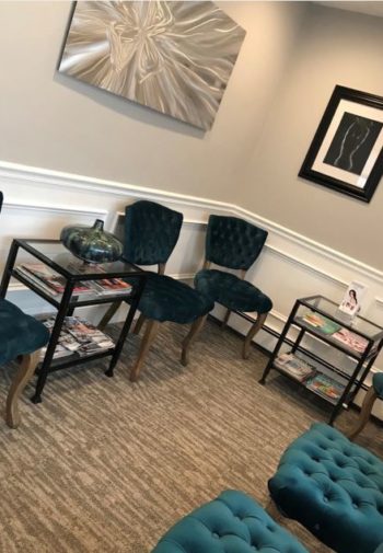 Beautiful newly designed waiting room equipped with 6 velvet turquoise chairs and glass tables for clients while waiting for hair removal.