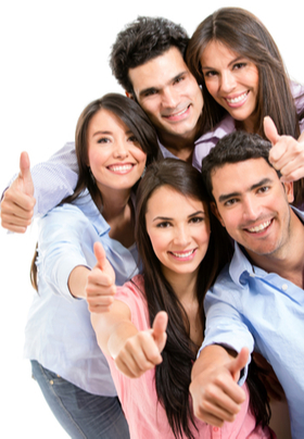 A group of 5 attractive young men and women all with brown hair huddling together giving a thumbs up.