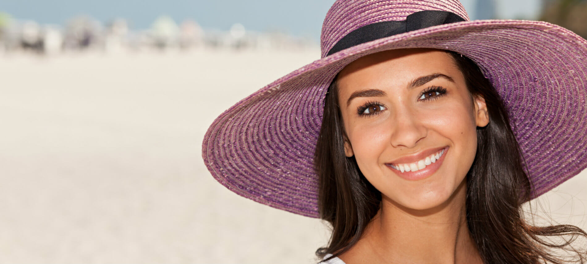 Smiling black hair woman wearing lavender sun hat after hair removal treatment