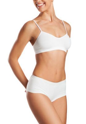 smiling woman in whit underwear with hands behind back after hair removal