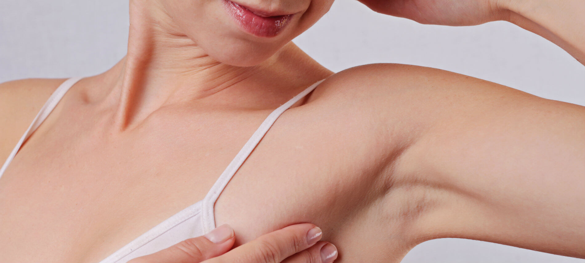 A woman holds the skin around her armpit as she examines the hair treatment and smooth skin.